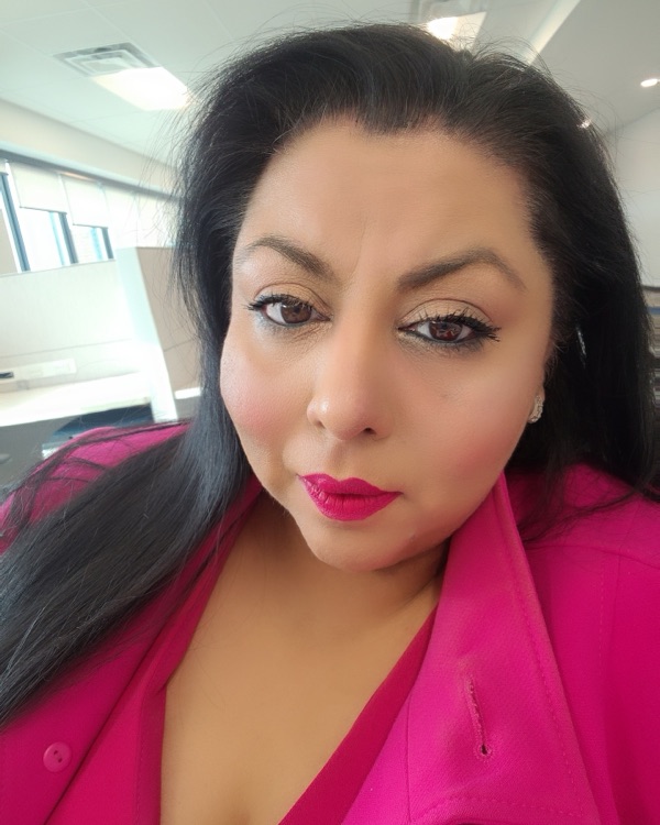Izza Masud, founder of Distilligent, wearing a bright pink blazer.